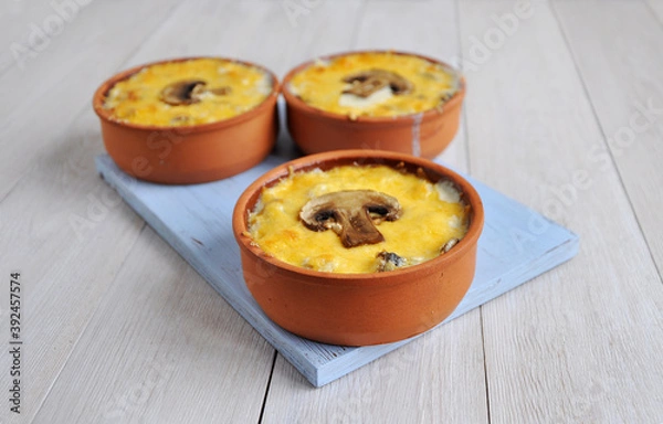 Fototapeta Homemade mushroom julienne in ceramic cocotte. Sliced champignons.