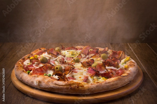 Obraz Delicious Portuguese Pizza made with ham, pea egg, heart of palm, pepperoni, onion and mozzarella and bacon. Hot from the wood oven still smoked. Pizzerias.