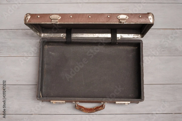 Fototapeta Retro style brown open empty suitcase on the wooden floor background.