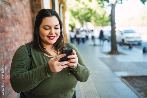 Obraz Young plus size woman using her mobile phone.