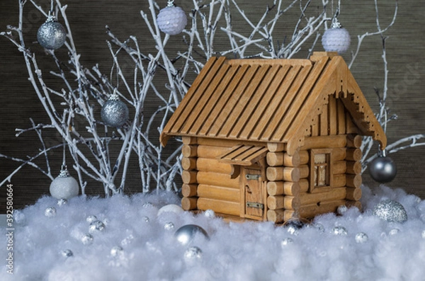 Fototapeta Mock-up of a wooden house in artificial snow on a background of white branches with glass balls. Christmas decor.