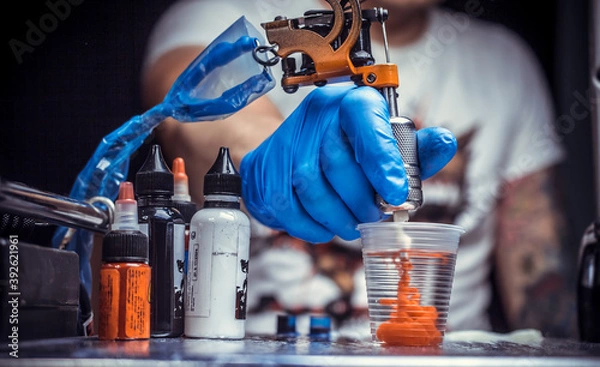 Obraz Hand of a tattoo artist, holding a tattoo machine.