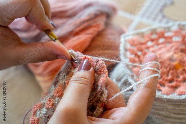 Obraz Female hands knitting with multi colored wool, top view.