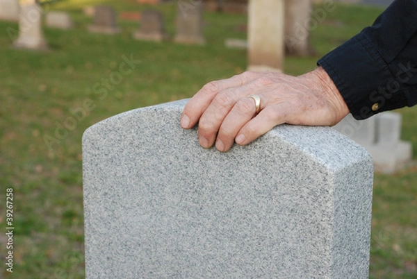 Obraz Man's hand resting on headstone