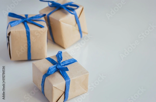 Fototapeta Gift boxes made from craft paper with blue ribbon on white background with copy space.