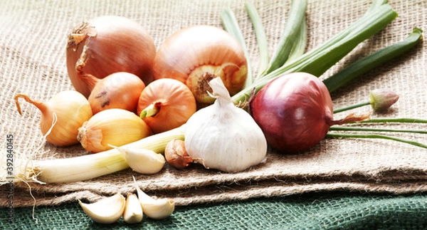 Fototapeta Onions, leek and garlic on jute, copy space