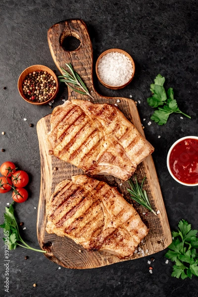 Fototapeta grilled pork steaks with spices on a stone background