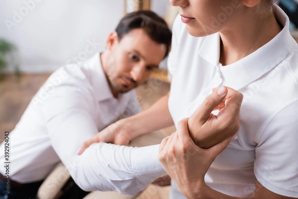 Fototapeta Masseuse doing arm massage for businessman on blurred background