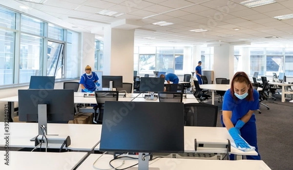 Fototapeta Professional cleaners with the masks on their faces clean and disinfect an empty office space