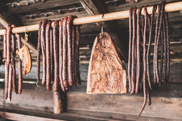 Obraz Smoked sausages and bacon hanging in row