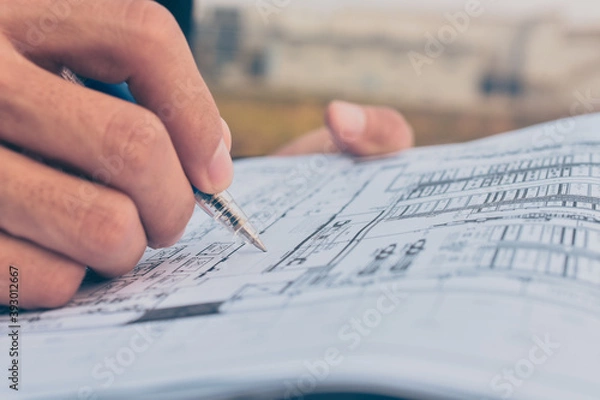 Obraz Close up hand write on paper blueprint checking building construction project