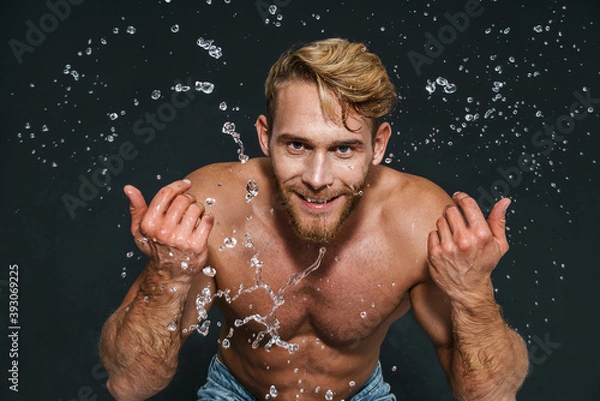 Fototapeta Happy caucasian shirtless man smiling while washing his face