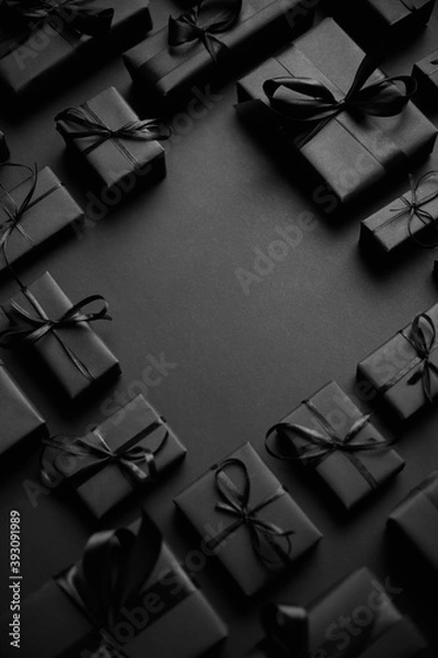 Fototapeta Arranged Gifts boxes wrapped in black paper with black ribbon on black background. Christmas concept
