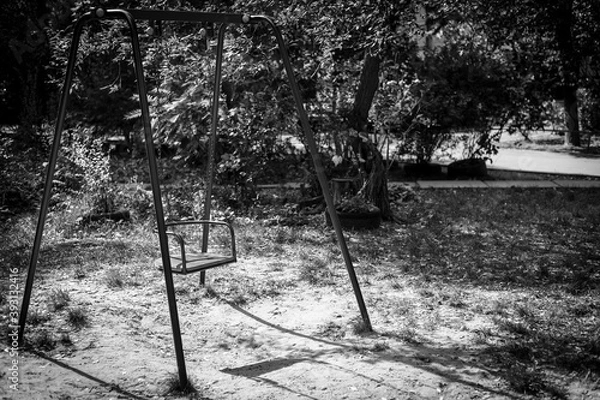 Fototapeta Empty swing in an abandoned playground. Gloomy swing