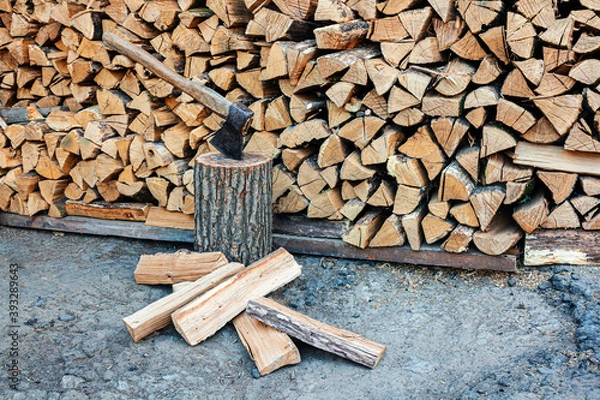 Fototapeta Old ax and a deck for chopping wood. Dry oak firewood stacked in a pile, chopped wood for winter heating of the fireplace. Natural wood background.