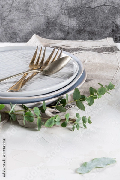 Fototapeta Empty plates and cutlery as mockup set on rustic home table decorated with eucalyptus leaves and branches. Top tableware for chef table decor and menu branding design