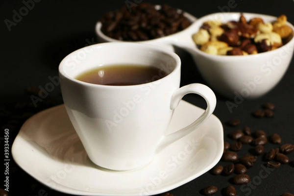 Fototapeta A cup of coffee with milk and coffee beans on a glass table. The concept of home comfort and warmth.