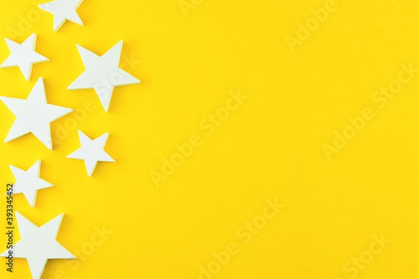 Fototapeta Zenithal view on a yellow background with white stars, representation of Christmas. Space for text or idea.