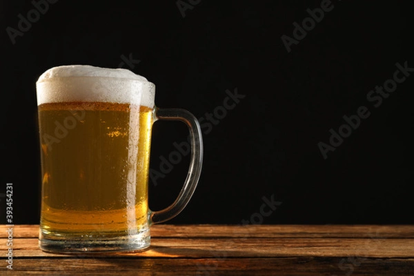 Fototapeta Cold tasty beer on wooden table against dark background. Space for text