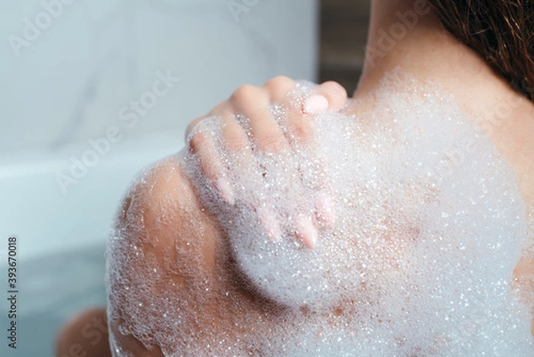 Obraz Close-up of a female shoulder in foam. The girl takes a bath with foam. Body care, skin care, asparagus procedures