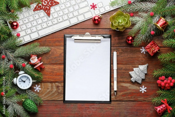 Fototapeta Christmas background and decoration with fir branches, computer keyboard, clipboard, pen, gift boxes and Christmas toys on old wooden board with copy space. 
