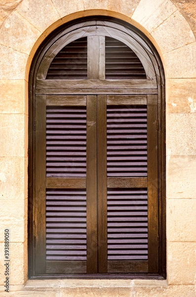 Fototapeta Arched window with closed shutters