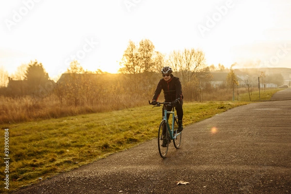 Fototapeta man on a blue bicycle in the morning cold season goes to work