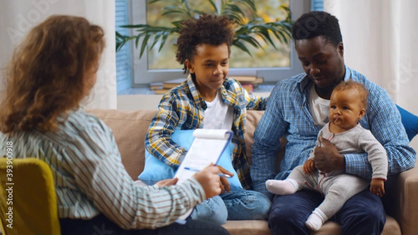 Fototapeta Social worker consulting smiling young single father with kids at home.