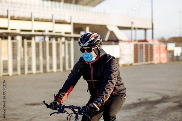 Fototapeta cyclist during quarantine rides a bicycle in a mask