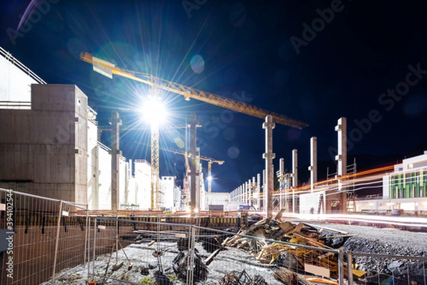 Obraz Floodlit tower crane on building construction site at night
