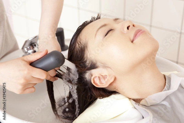 Obraz 美容師にトリートメントを流してもらう女性