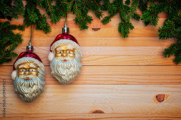 Fototapeta Christmas or New Year decoration background with hanging two Santa Clauses in pine branches on a wooden table with copy space.