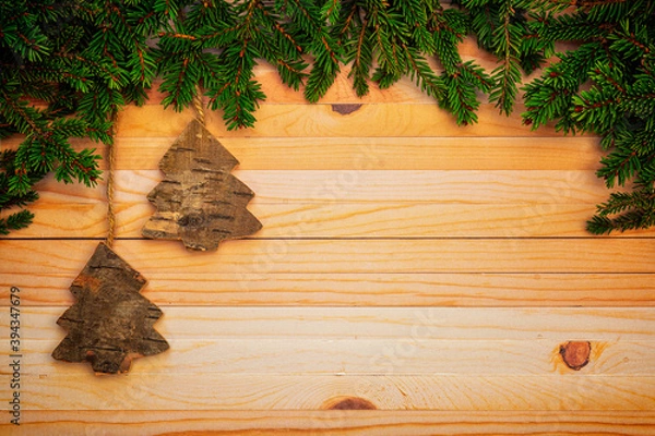 Fototapeta Christmas or New Year decoration background with hanging brown trees in pine branches on a wooden table with copy space.