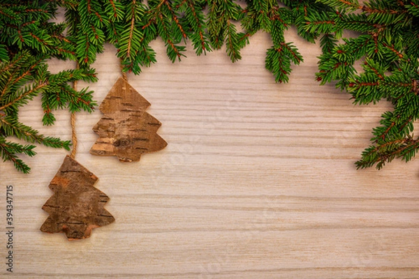 Fototapeta Christmas or New Year decoration background with hanging brown trees in pine branches on a wooden table with copy space.