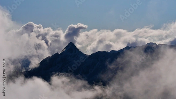 Obraz Mystic view of the silhouettes of rugged mountains in the European Alps surrounded by rising clouds above Montafon valley, Austria in autumn season.