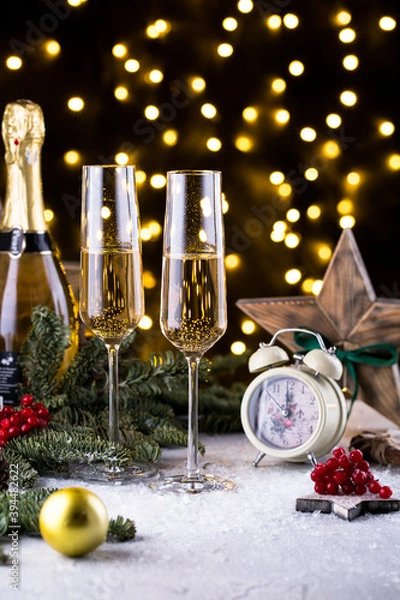 Fototapeta Two glasses of sparkling champagne at New year eve night with clock and bokeh background. Christmas decoration dinner table setting, copy space