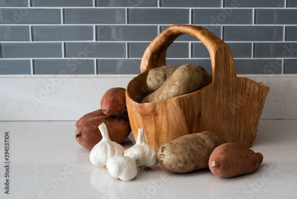 Fototapeta Basket made of wood with Russet potatos, sweetpoitatos and 3 bulbs of garlic