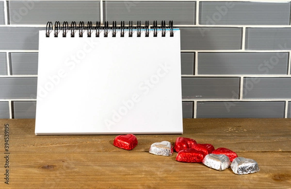 Fototapeta Blank spiral notepad in a modern kitchen with silver and red heart chocolates