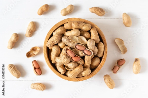 Obraz Top view of peanuts in a wooden bowl on white background,