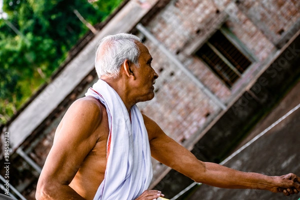 Obraz Close-up Portrait of Indian Senior Man Arching. Happy alone side facing old man, wearing white dress, giving pose with style at the camera. Elderly Man Is Enjoying Retirement In Nature In Afternoon.