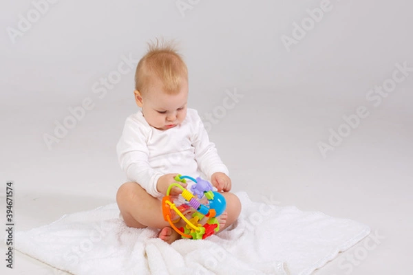 Fototapeta baby playing with a colorful toy isolated on a white background