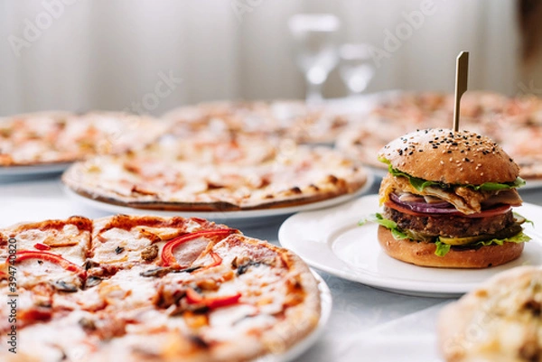 Fototapeta Assorted different pizzas and burgers on the table for tasting or working out the menu, side view