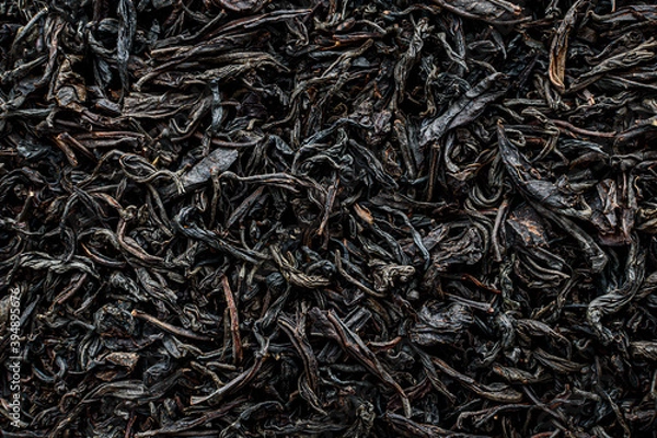 Fototapeta black dry large leaf tea as background texture, selective focus