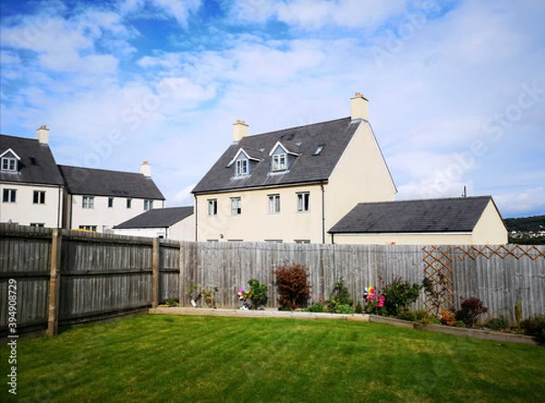 Obraz Rear garden of a modern house on a housing estate with a lawn, flower boarder and high paneled fence on a sunny summer day - UK