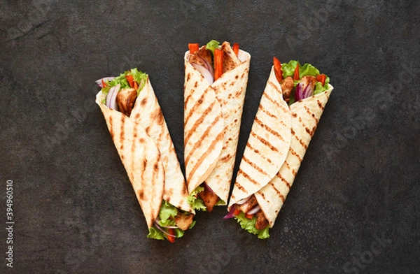 Fototapeta Mexican tortilla grilled wrap with chicken breast and vegetables on concrete background