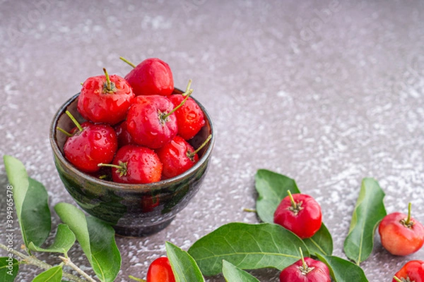 Fototapeta Ripe red cherries in a ceramic dish with leaves on a wooden table. Space for text. Sweet organic berries. Concept of healthy fruits