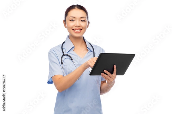 Fototapeta medicine, profession and healthcare concept - happy smiling asian female doctor or nurse in blue uniform with tablet pc computer and stethoscope over white background