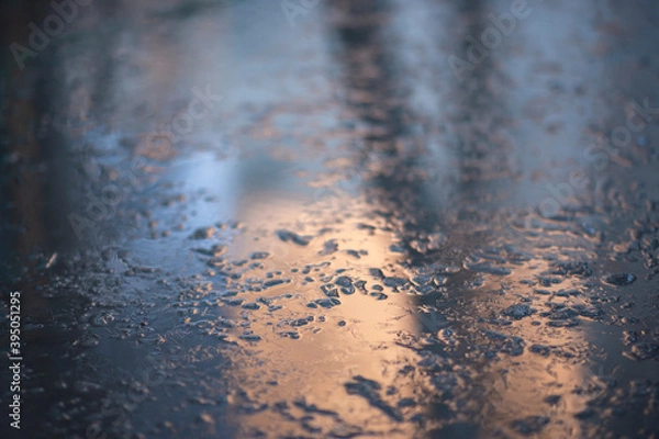Fototapeta Frozen water in a puddle. Sunlight reflects off the frozen surface of the puddle. Natural phenomenon, abstract background.