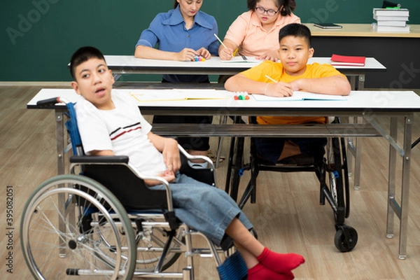 Obraz disability boy sitting on wheelchair in classroom special with teacher and AUtism kids education