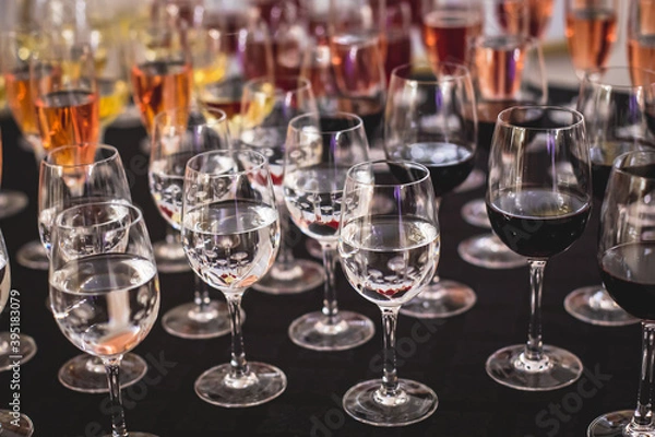 Fototapeta Line of alcohol setting on catering banquet table, bartender pouring beverages, row of different colored alcohol cocktails on a party, martini, vodka, and others on decorated banquet table event